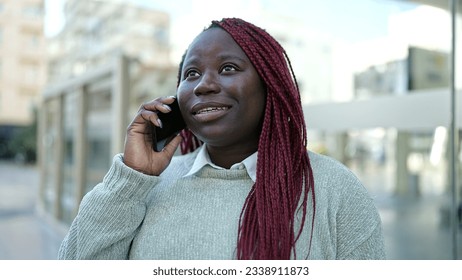 African woman with braided hair speaking on the phone at street - Shutterstock ID 2338911873