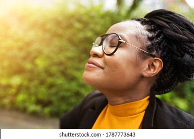 African Woman Breathing Clean Air In Nature With Eyes Closed