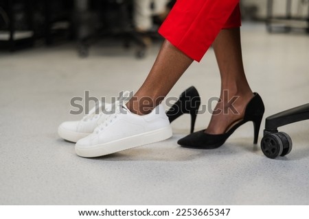 African woman changing from high heels to sneakers in the office. Tired legs.  商業照片 © 