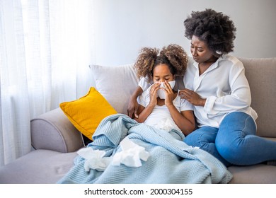 African Woman Checking Temperature With Hand Of Little Ill Daughter. Mother Checking Temperature Of Her Sick Indian Girl. Sick Child Lying On Bed Under Blanket With Woman Checking Fever On Forehead