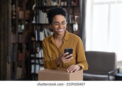 African woman client of easy trusted e-services online shipping, make order, use cellphone typing to courier, prepare parcel box for sending to friend abroad use reliable company of delivery services - Shutterstock ID 2159105457