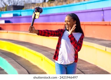 African woman content creator recording a live video in social media in a colorful park - Powered by Shutterstock