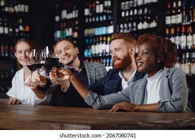 African woman and European men are mingled with glasses of red wine in restaurant. Concept Multicultural friendship.