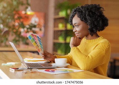 African Woman Graphic Designer Working With Color Sets At Cafe, Using Laptop And Drinking Coffee, Empty Space