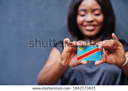 African woman hold small DR Congo flag in hands.