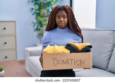 African woman holding donations box for charity relaxed with serious expression on face. simple and natural looking at the camera.  - Shutterstock ID 2237435837