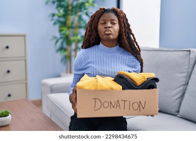 African woman holding donations box for charity looking at the camera blowing a kiss being lovely and sexy. love expression.  - Shutterstock ID 2298434675