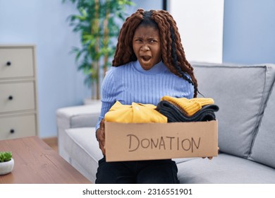 African woman holding donations box for charity angry and mad screaming frustrated and furious, shouting with anger. rage and aggressive concept.  - Shutterstock ID 2316551901