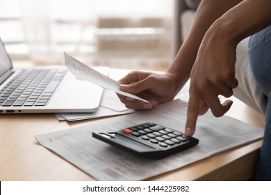 African woman holding paper bills using calculator, close up vie