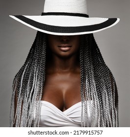 Afrikanische Frau mit langer Haare. Schwarz-Weiß-Konzept. Schönheitsmodell im verborgenen Gesicht von Big Hut. Afro Frisur und Lippen Make-up. Sexy Mysterious Women Portrait auf grauem Hintergrund