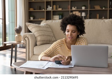 African woman makes calculations calculator pay utility bills  loan via e  bank application computer  sit in living room alone  Personal family budget management  modern tech  accounting concept
