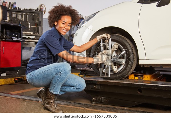 African woman as a mechatronics apprentice\
does a wheel alignment on the landing\
gear