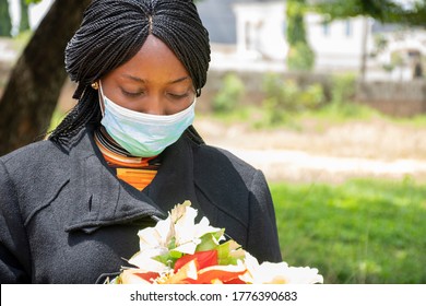 African Woman Mourning, Wearing Black And Holding Flowers