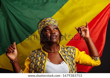 African woman in national clothes posing and dancing with Thumbs up against flag of Congo Republic