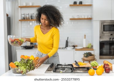 African woman preparing healthy food cooking vegetables and fruits in kitchen, healthy lifestyle, fresh ingredients meal preparation, nutrition, organic produce, culinary, kitchen activity at home - Powered by Shutterstock