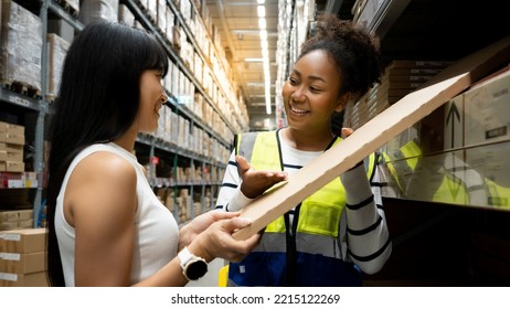 African woman Seller in building materials store advises buyer on goods for DIY house furniture. Seller and customer are talking standing between shelves in store. Hardware shopping concept. - Shutterstock ID 2215122269