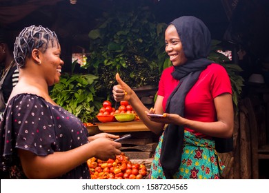 African Woman Selling In A Local Food Market Gives A Thumbs Up To A Customer To Confirm Successful Payment Via Mobile Phone Transfer