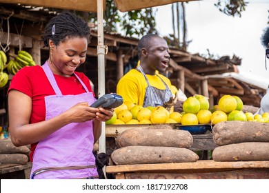 African Woman Selling In A Local Market Using A Pos Machine And Smiling