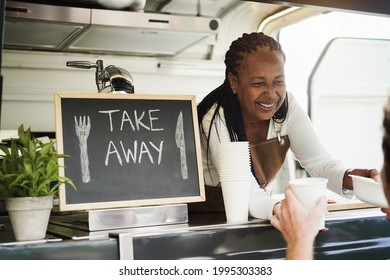 African Woman Serving Takeaway Food With Eco Paper Boxes Inside Food Truck - Focus On Face