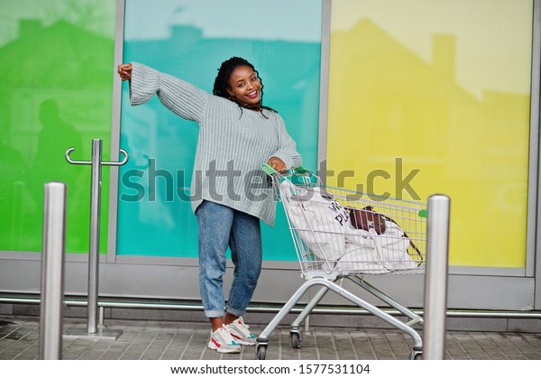 African woman with shopping cart trolley posed\
outdoor market.