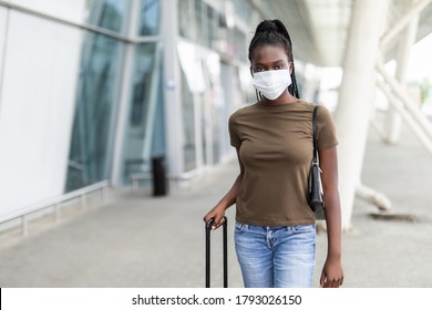 African Woman Is Sitting At The Airport With A Laptop In A Medical Mask. Young Girl Is Waiting For Departure At The Gate, Working Online. Social Responsibility, Virus Protection.