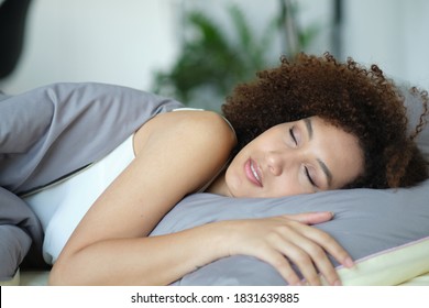 african woman sleeping in her bed at night, she is resting with eyes closed. Cozy bedtime. lady hugging soft white pillow. Lady enjoys fresh soft bedding linen and mattress in bedroom