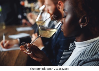 African Woman Sommelier Bartender Smelling White Wine And Making Degustation Card.