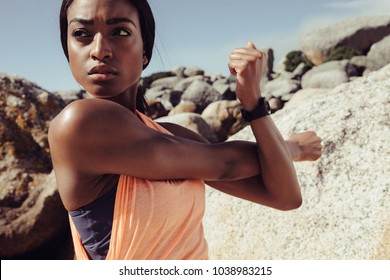 African woman stretching arms at the beach. Fitness female doing warmup workout and looking away outdoors. Closeup shot. - Powered by Shutterstock