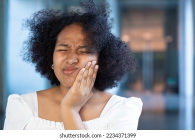 African woman suffering from toothache, tooth decay, tooth sensitivity, wisdom tooth pain, cavity, dental care concept - Shutterstock ID 2234371399