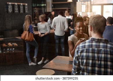 African Woman At Table In A Busy Modern Coffee Shop