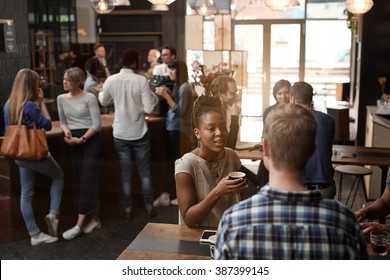 African Woman Talking With Friend Inside Busy Coffee Shop