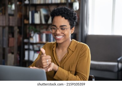 African woman teach learner via video call on laptop sit at desk show symbols with hands use gestures at remote lesson of sign language. Online speech therapist work, deaf-mute make videocall concept
