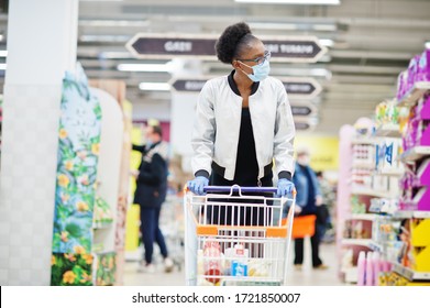 African woman wearing disposable medical mask and gloves shopping in supermarket during coronavirus pandemia outbreak. Epidemic time.