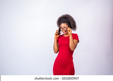 African Woman Wearing A Red Dress And Glasses Making A Phone Call, Gives A Cheeky Wink