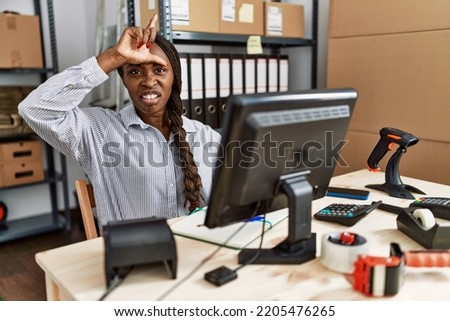 African woman working at small business ecommerce making fun of people with fingers on forehead doing loser gesture mocking and insulting. 