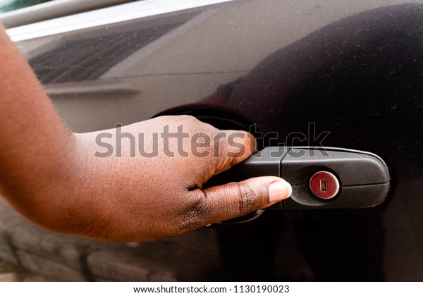 African\
woman\'s hand opening car door, close up or Black Girl\'s hand\
pulling a car\'s door handle. African American hand on handle\
opening a car door for service delivey\
concept