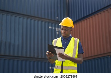 African worker holding document, walking and checking the containers box from cargo ship for export and import
