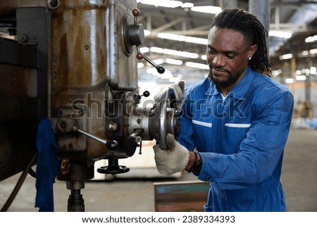 African worker or technician checking and control lathe machine in factory
