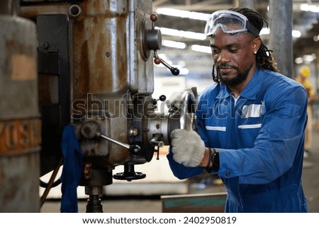 African worker or technician checking and control lathe machine in factory