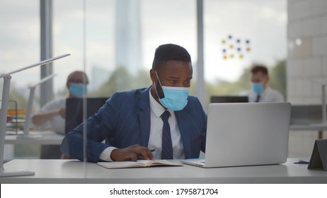 African worker wearing face protective mask using laptop computer working at office. Employees in medical masks at desktop working in office during epidemic outbreak