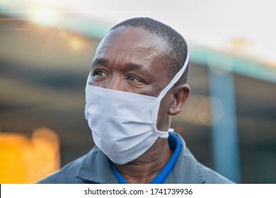 African Worker  Wearing A Mask, Working At A Chemical Factory Producing Bulk Hand Sanitizer 