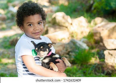 African Young Boy Holding His Little Dog In Nature.