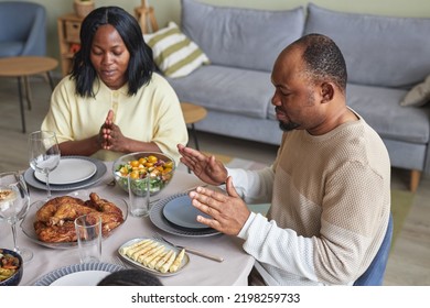 African Young Couple Praying At Dining Table Before Dinner In Living Room