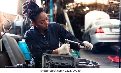 African young female car mechanic checking and fixing car engine at service car garage. Black woman mechanic working in car service and maintenance workshop. - Powered by Shutterstock