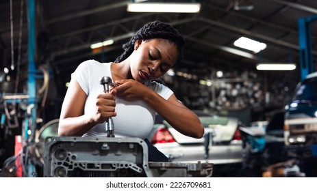 African young female car mechanic checking and fixing car engine at service car garage. Black woman mechanic working in car service and maintenance workshop. - Powered by Shutterstock