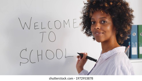 African Young Female Teacher Writing Welcome To School On White Board In Classroom. Afro-american Woman University Professor Or Tutor Writing On Whiteboard In College Class