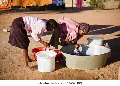 african young girl and an elderly woman washing clothes in the yard