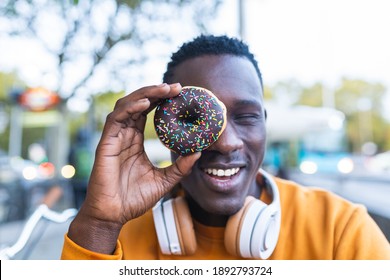 African Young Man Eating Donuts Outdoors. Black Man Eating Sweet Food While Smiling. Food Concept. - Powered by Shutterstock