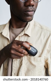 African young man in eyeglasses putting the case with wireless headphones into his pocket