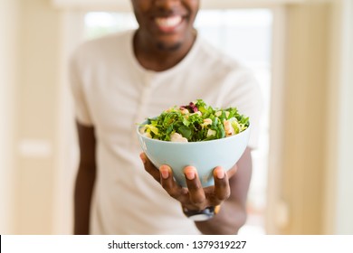 African Young Man Holding A Bowl Of Healthy Salad Smiling Cheerful